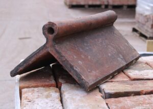 Elegant reclaimed fancy ridge tile with a red roll top design, angled at 105 degrees, showcasing the rich red hue and smooth, timeless contour that adds unparalleled beauty to roofing projects.
